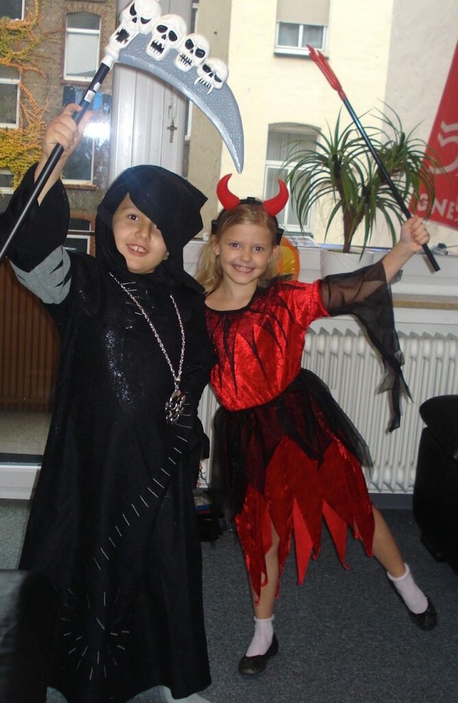 5 Kinder in Halloweenkostümen feiern.